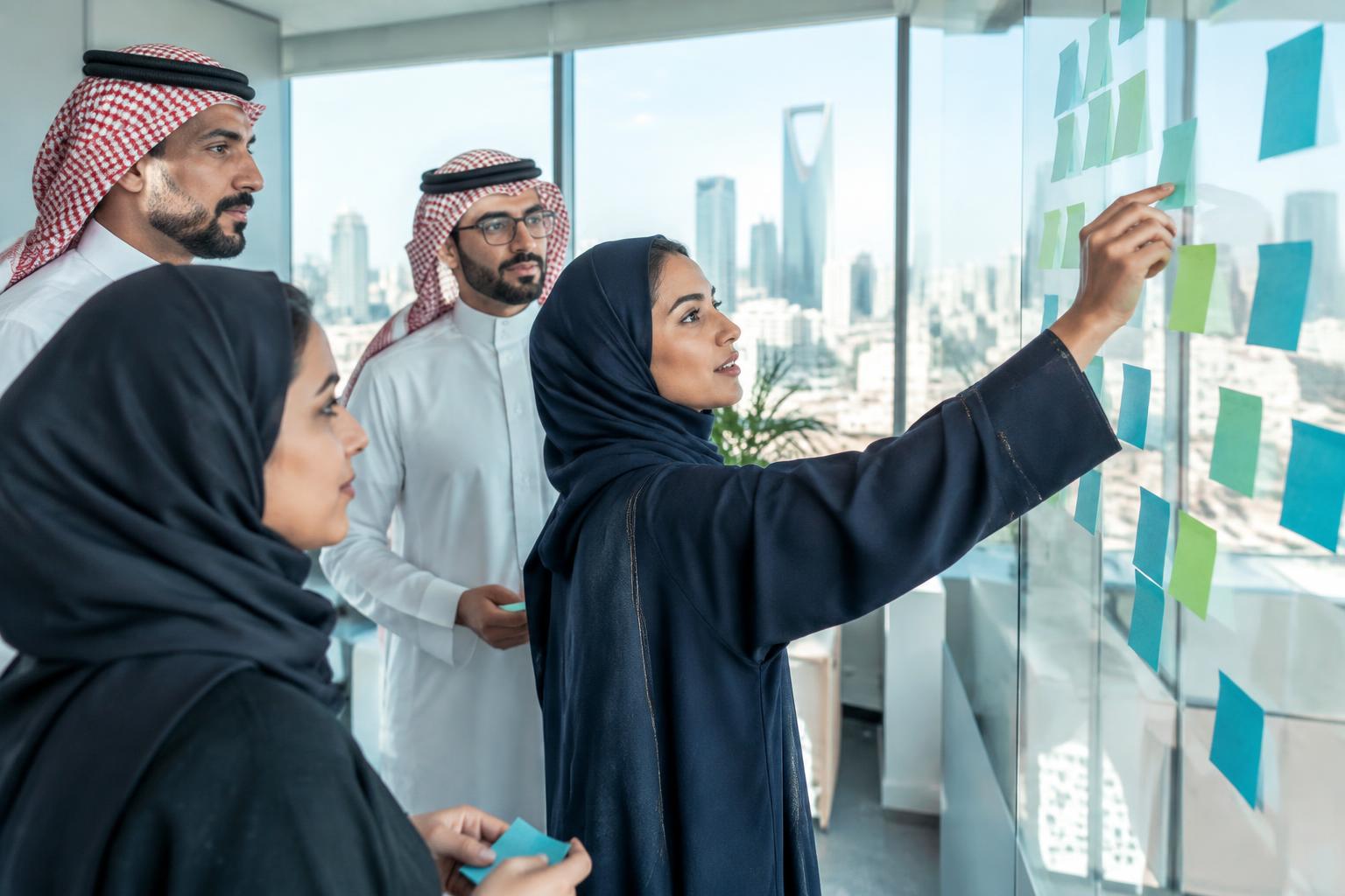 فريق عمل سعودي يرسم مسار إجراء باستخدام ملاحظات لاصقة